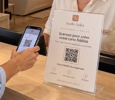Support QR du programme de fidélité posé sur le comptoir d’accueil d’un centre de bronzage, scanné par une cliente