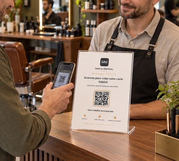 Support QR du programme de fidélité posé sur le comptoir d’un barbier, scanné par un client