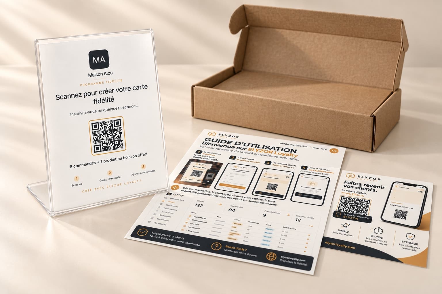 Le kit physique ELYZOR : support comptoir avec la fiche QR Maison Alba, guide de lancement et boîte d’expédition.